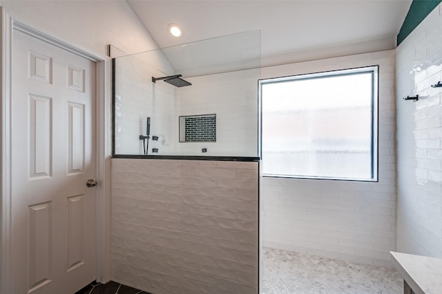 full bathroom with a wealth of natural light, walk in shower, tile patterned floors, and vaulted ceiling