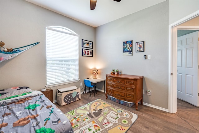 bedroom featuring multiple windows, a ceiling fan, baseboards, and wood finished floors