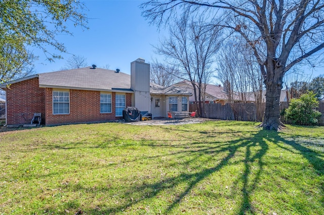 back of property with brick siding, a lawn, a patio, and fence