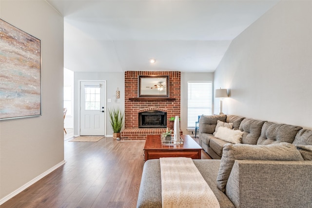 living room with a fireplace, vaulted ceiling, wood finished floors, and baseboards