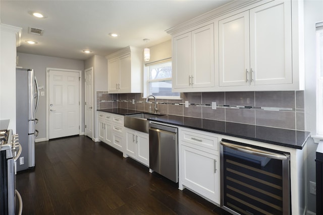 kitchen with beverage cooler, visible vents, a sink, appliances with stainless steel finishes, and backsplash