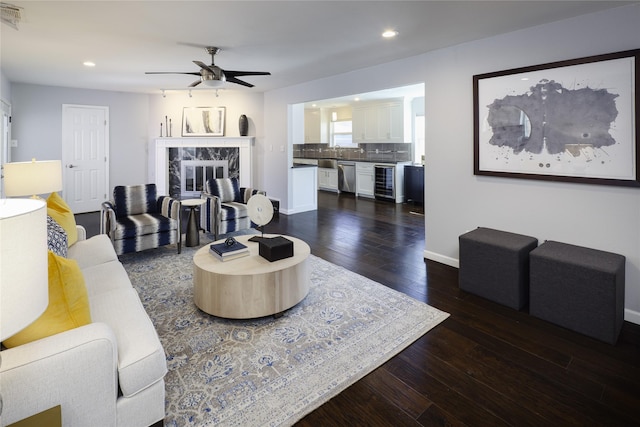 living room with beverage cooler, baseboards, dark wood finished floors, recessed lighting, and a high end fireplace