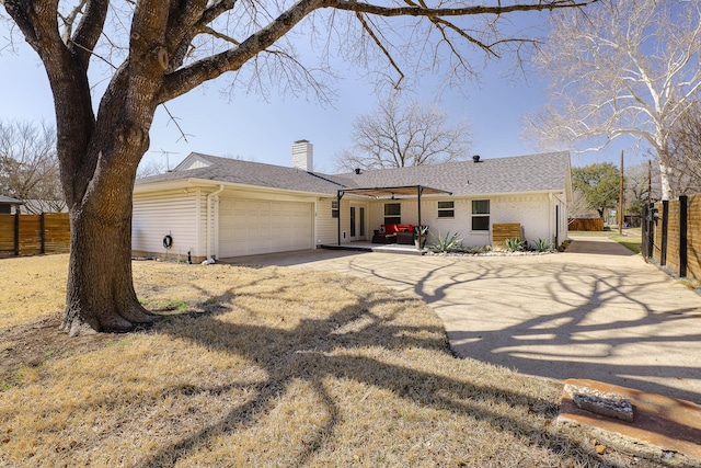 ranch-style home featuring an attached garage, a chimney, driveway, and fence