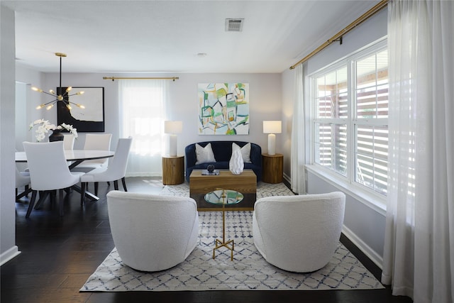 living area featuring visible vents, baseboards, a healthy amount of sunlight, and wood finished floors