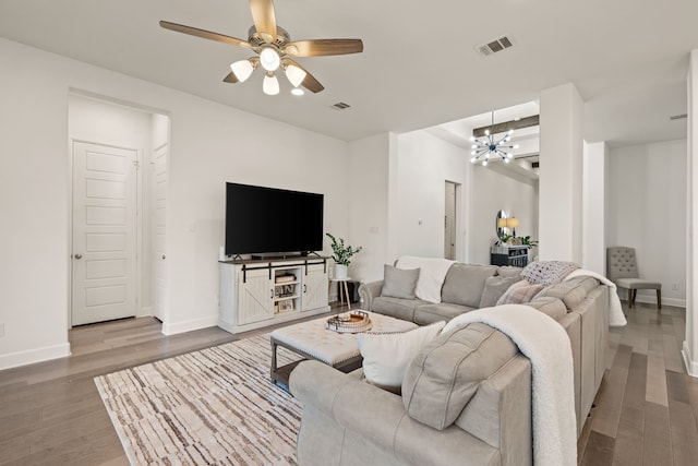 living area featuring ceiling fan with notable chandelier, wood finished floors, visible vents, and baseboards