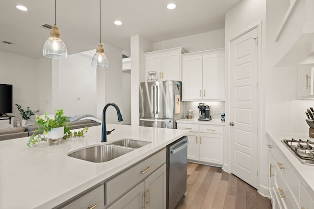 kitchen featuring wood finished floors, a sink, light countertops, appliances with stainless steel finishes, and decorative light fixtures