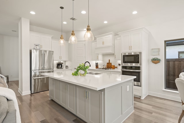 kitchen with backsplash, light countertops, stainless steel appliances, white cabinetry, and a sink