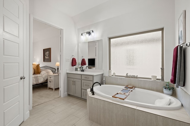 bathroom featuring vanity, ensuite bath, a bath, and wood finished floors