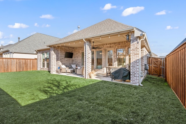 back of house featuring a patio, a fenced backyard, a yard, roof with shingles, and brick siding