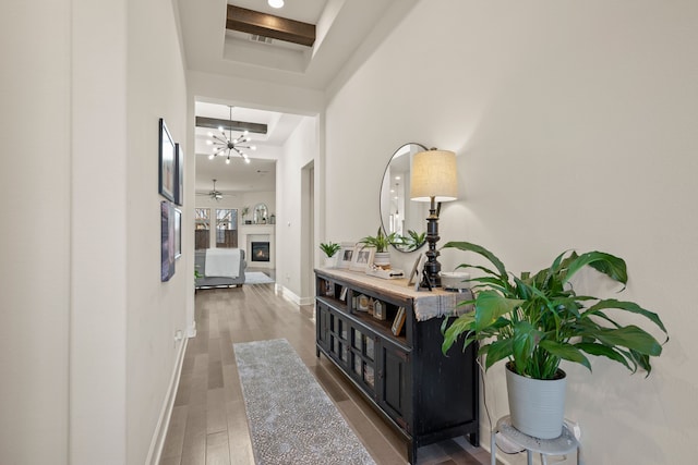 corridor with baseboards, a raised ceiling, and wood finished floors