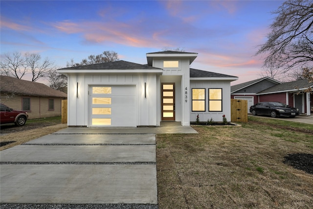 view of front of property featuring driveway, a shingled roof, a front lawn, a garage, and board and batten siding