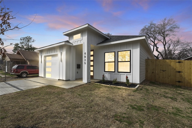 view of front facade with fence, a yard, concrete driveway, a garage, and board and batten siding