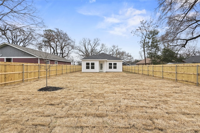 back of house featuring a lawn and a fenced backyard