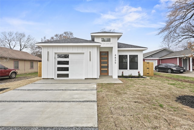 view of front of house with board and batten siding, concrete driveway, roof with shingles, a front yard, and a garage