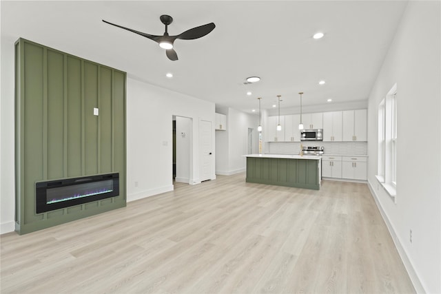 unfurnished living room featuring recessed lighting, baseboards, a large fireplace, and light wood-style floors