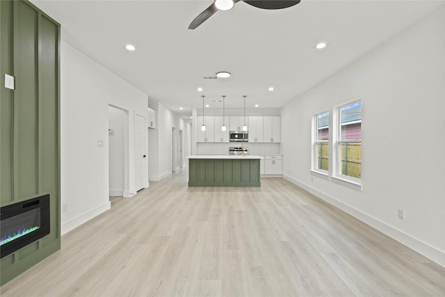 unfurnished living room with a ceiling fan, recessed lighting, baseboards, and light wood finished floors