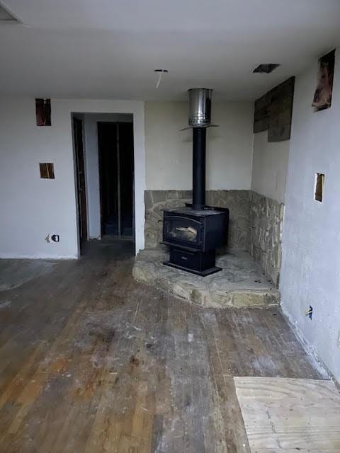 unfurnished living room featuring hardwood / wood-style floors and a wood stove