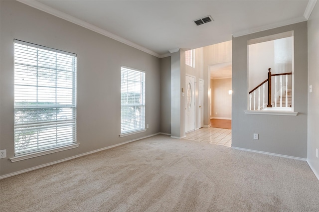 carpeted spare room featuring crown molding, baseboards, and visible vents