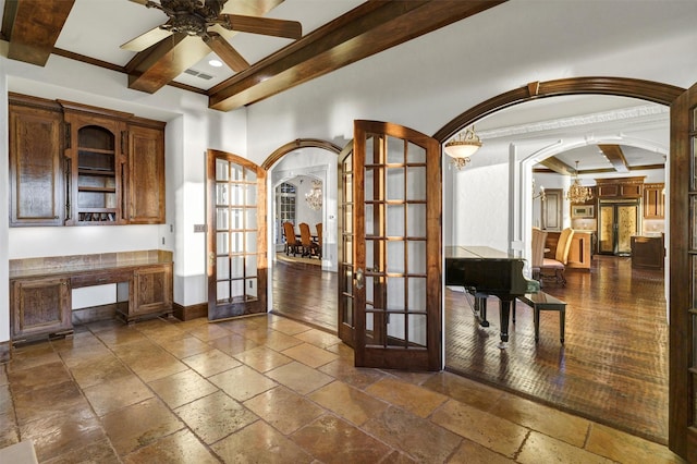 dining space with stone tile floors, baseboards, beam ceiling, arched walkways, and french doors