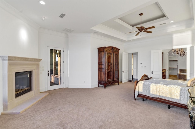 bedroom with visible vents, ornamental molding, a glass covered fireplace, carpet, and a raised ceiling