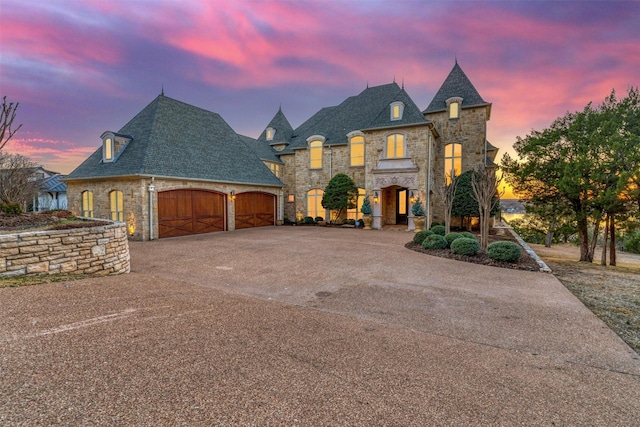 french provincial home with stone siding, concrete driveway, and an attached garage