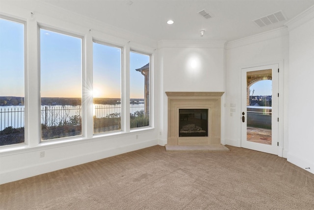 unfurnished living room with a glass covered fireplace, visible vents, carpet, and ornamental molding