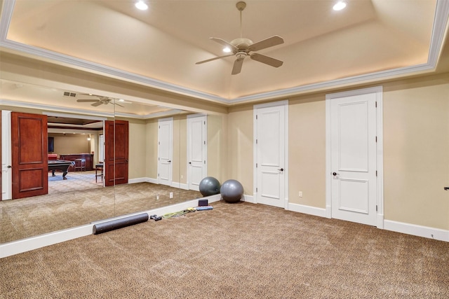 exercise room featuring a ceiling fan, baseboards, carpet, crown molding, and a raised ceiling