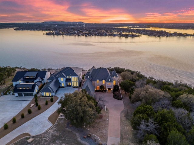 aerial view at dusk with a water view and a residential view