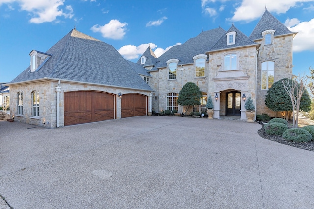 french country inspired facade featuring a high end roof, driveway, and stone siding