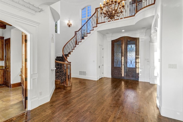 foyer with visible vents, arched walkways, wood finished floors, and stairway