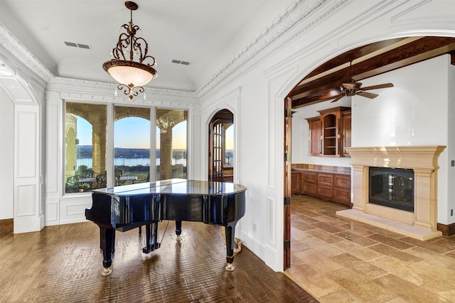 sitting room with arched walkways, visible vents, stone tile floors, and vaulted ceiling