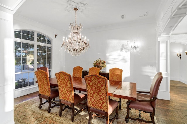 dining room featuring a chandelier, wood finished floors, ornate columns, and ornamental molding