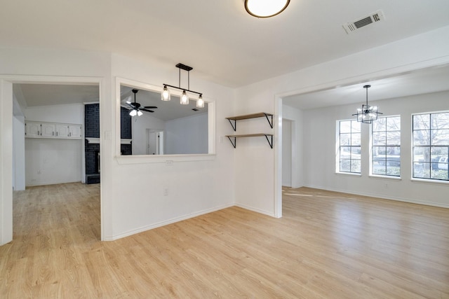 interior space featuring visible vents, baseboards, vaulted ceiling, light wood-style floors, and ceiling fan with notable chandelier