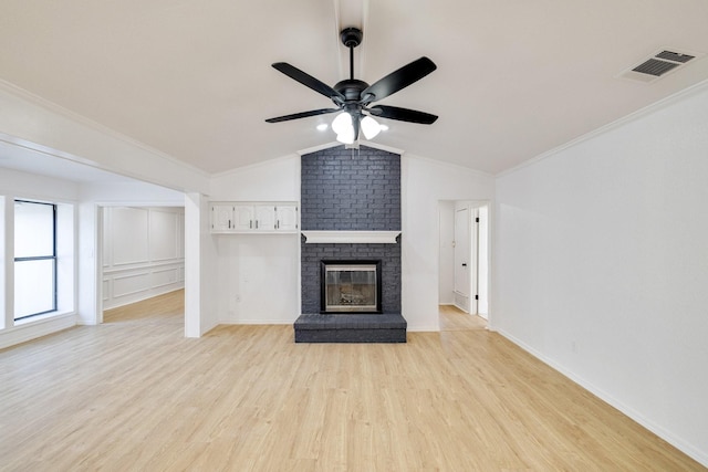 unfurnished living room with visible vents, a brick fireplace, ornamental molding, vaulted ceiling, and light wood-style flooring