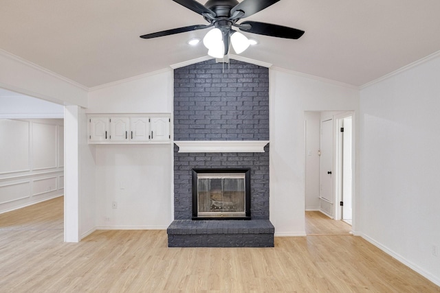 unfurnished living room with crown molding, baseboards, vaulted ceiling, light wood-style flooring, and a fireplace