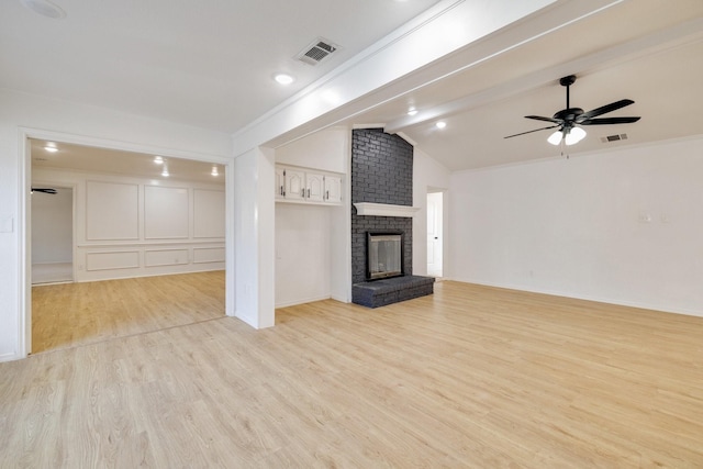 unfurnished living room with lofted ceiling with beams, a brick fireplace, light wood-style flooring, and visible vents