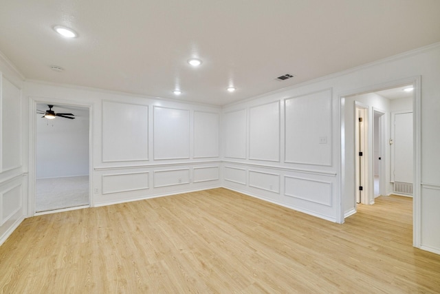 spare room featuring a decorative wall, light wood-type flooring, and ornamental molding