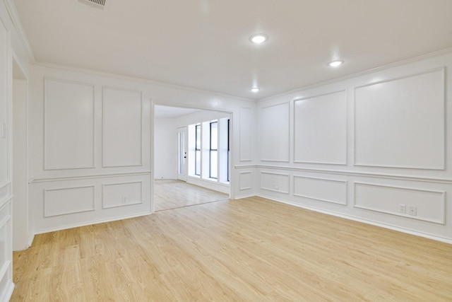 unfurnished room featuring visible vents, recessed lighting, light wood-style floors, crown molding, and a decorative wall