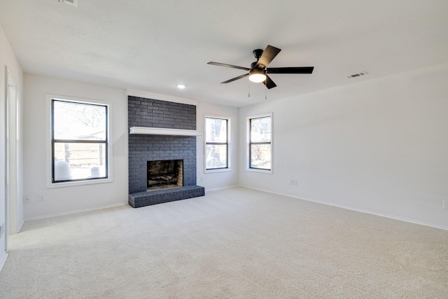 unfurnished living room with a brick fireplace, carpet, visible vents, and a healthy amount of sunlight