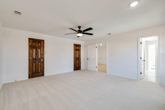 carpeted spare room with visible vents and ceiling fan