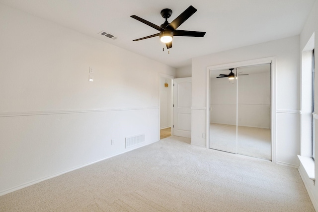 unfurnished bedroom with a closet, visible vents, ceiling fan, and carpet