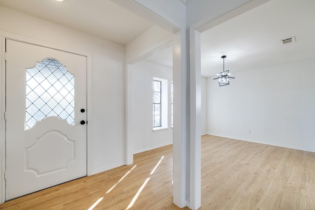 foyer featuring light wood-type flooring, visible vents, baseboards, and a chandelier