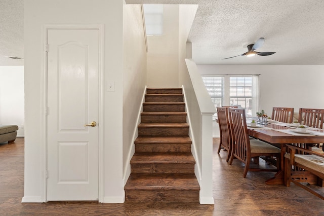 stairs featuring visible vents, a textured ceiling, wood finished floors, baseboards, and ceiling fan