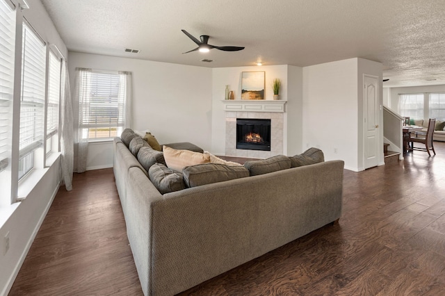 living room with visible vents, dark wood-type flooring, ceiling fan, and a textured ceiling