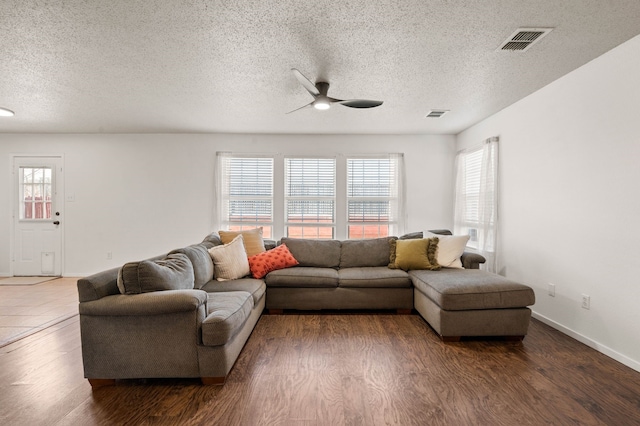 living area with visible vents, a textured ceiling, a ceiling fan, and wood finished floors