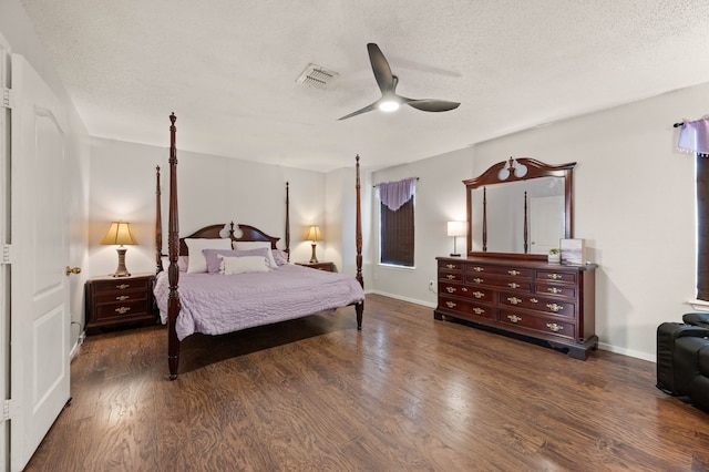 bedroom featuring visible vents, a textured ceiling, baseboards, and wood finished floors