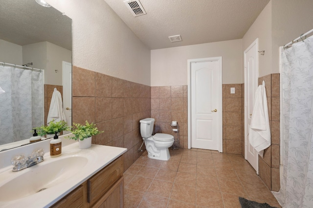 full bath featuring tile patterned flooring, visible vents, toilet, vanity, and a textured ceiling