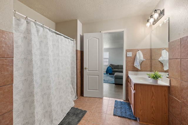 full bath featuring vanity, tile patterned floors, tile walls, and a textured ceiling