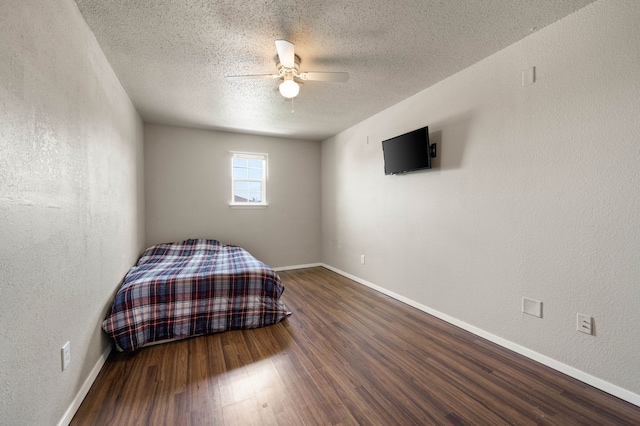 unfurnished bedroom featuring baseboards, wood finished floors, and a textured wall