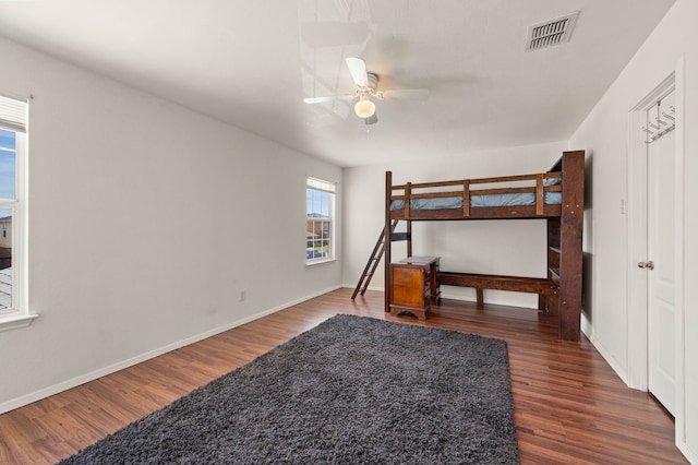 bedroom with visible vents, baseboards, wood finished floors, and a ceiling fan